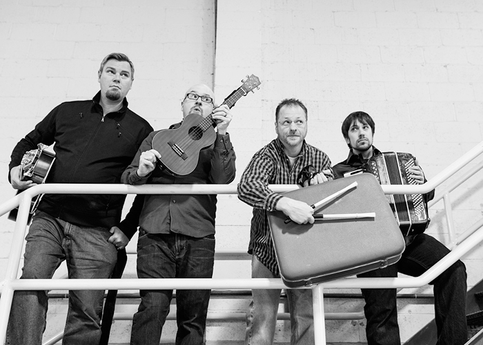 four men stand on a staircase holding instruments