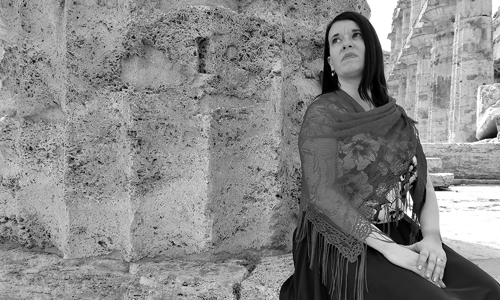 a black and white photo of a woman with dark hair wearing a shawl