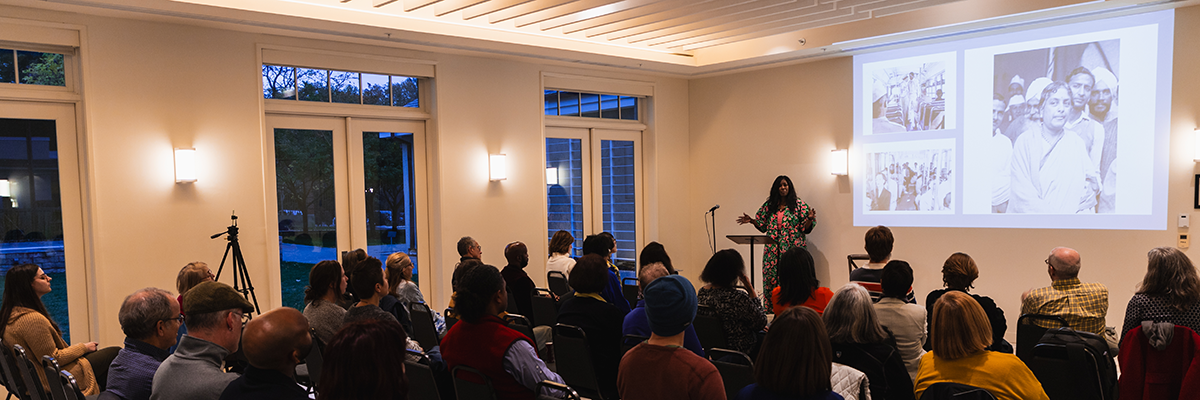an indoor event space filled with people sitting in chairs listening to a lecture