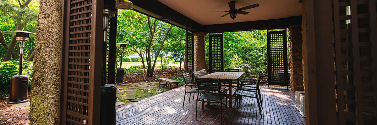 an outdoor covered patio with a table and chairs