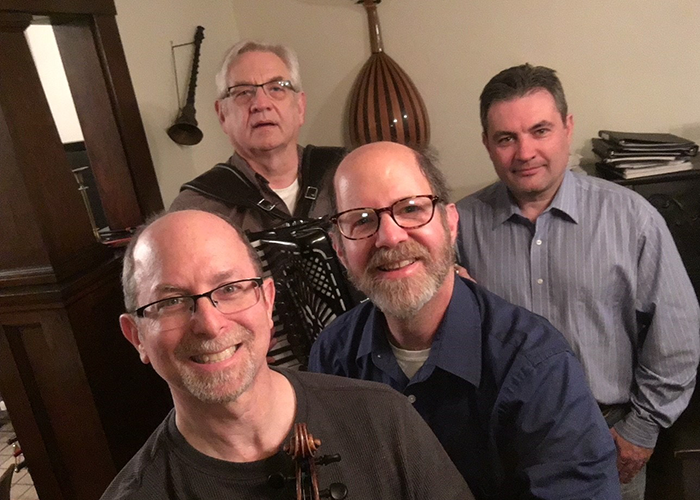 four men stand in front of a collection of instruments