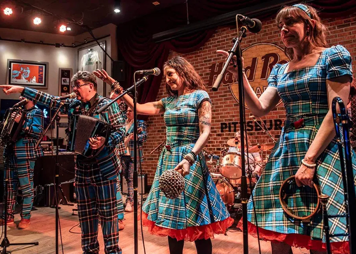 a group of musicians in plaid clothing play on stage