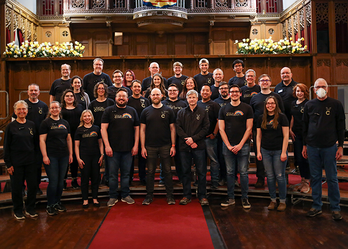 a large choir in black t-shirts stands in a church