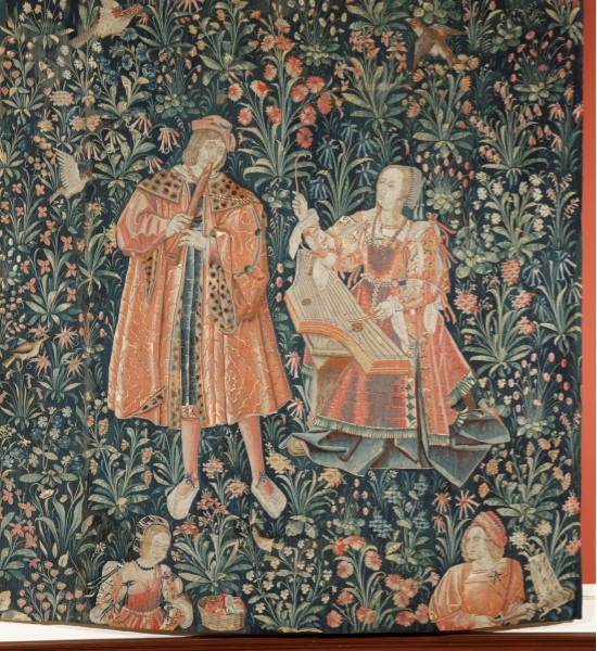 a woven tapestry showing a man playing flute and a woman playing a harp