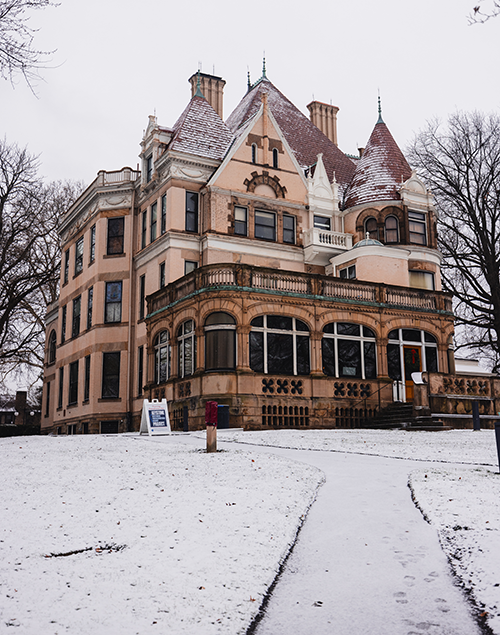 exterior view of a gilded age mansion, surrounded by a dusting of snow