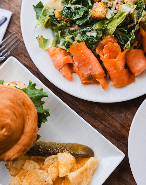 a sandwich and chips and a salad with smoked salmon