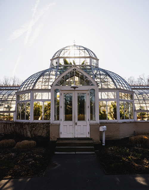 the exterior of a historic greenhouse at sunrise