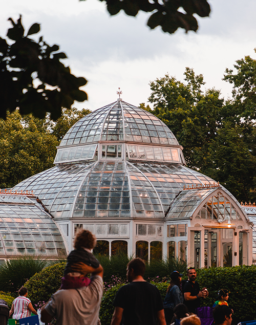 a greenhouse at sunset with people in the foreground
