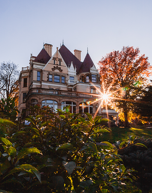 exterior view of a gilded age mansion surrounded by fall foliage