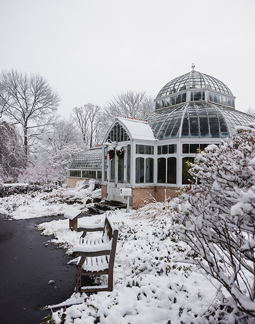 the exterior of a historic greenhouse surrounded by snow