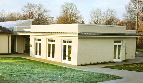 A white building with several doors behind a lawn