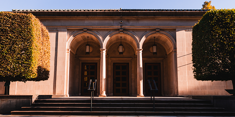 the fracade of a museum, with pillars and arches framing three doors