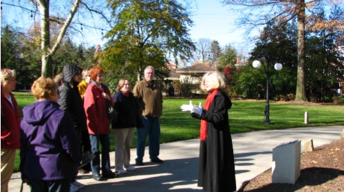 a group of people listen to a tour guide giving a guided tour of the historic clayton home