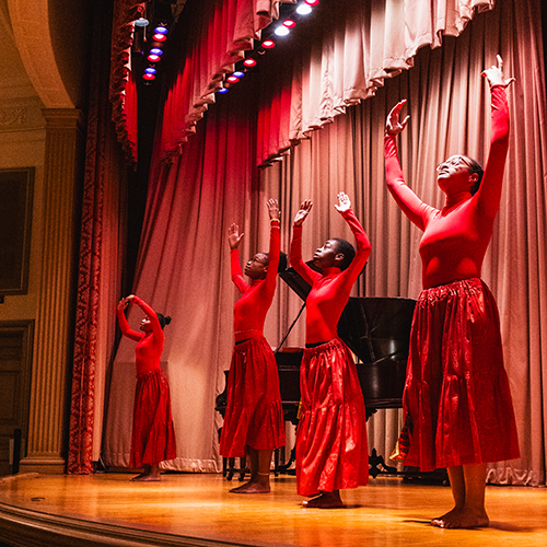 four young dancers in red dresses perform on stage